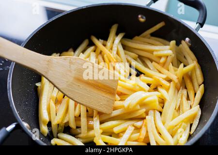 Cottura delle patate fritte in una padella. Patate a fette con spezie Foto Stock