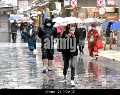 Hong Kong, Cina. 21st Feb 2022. Le persone che indossano maschere per il viso camminano su una strada a Hong Kong, Cina meridionale, 21 febbraio 2022. Hong Kong lunedì ha segnalato 7.533 nuovi casi e 13 morti di COVID-19, dati ufficiali mostrati. Credit: Lo Ping Fai/Xinhua/Alamy Live News Foto Stock