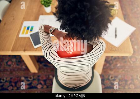 Soffrite di un collo rigido. Scatto ad angolo alto di una giovane donna che avverte dolore al collo mentre lavora da casa. Foto Stock