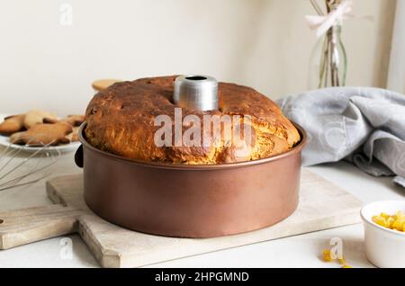 Torta in uno stampo di alluminio su un tagliere di legno in cucina. Una torta dolce, alta e deliziosa cotta al forno per una cena in famiglia. Il concetto di casa f Foto Stock