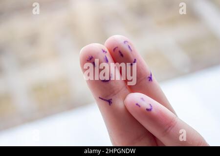 Volti sorridenti disegnati sulle dita. Madre, padre e bambino felice concetto di famiglia. Foto Stock