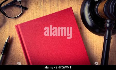 Vista dall'alto del libro bianco di copertina rosso con il gavel come sfondo. Foto Stock