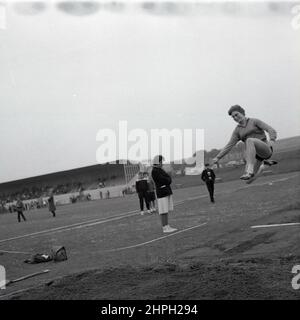 1960s, storica, un atleta femminile che fa il salto lungo ad un concorso di atletica, Fife, Scotand, Regno Unito. Foto Stock