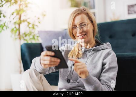 Biondo utilizzando lo smartphone a casa Foto Stock
