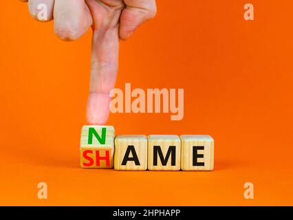 Nome o simbolo di vergogna. Businessman trasforma il cubo di legno e cambia la parola concetto vergogna in Nome. Bella tavola arancione sfondo arancione, copia spa Foto Stock