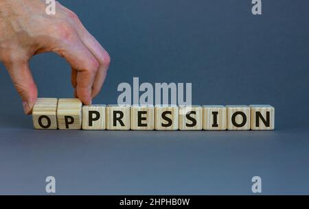 Pressione al simbolo di oppressione. L'uomo d'affari trasforma i cubi di legno, cambia la parola pressione in oppressione. Bellissimo sfondo grigio. Affari, pressione Foto Stock