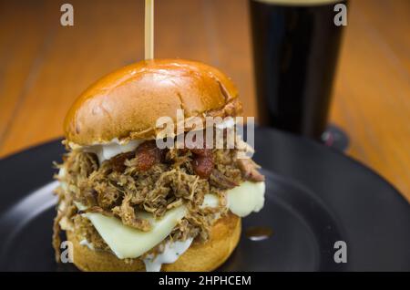 Primo piano di gustosi hamburger di maiale fatti in casa tirati su un tavolo di legno e sfondo nero Foto Stock