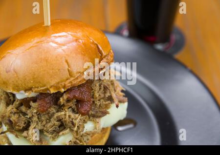 Primo piano di gustosi hamburger di maiale fatti in casa tirati su un tavolo di legno e sfondo nero Foto Stock