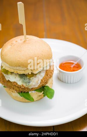 Primo piano di gustosi hamburger di pollo fatti in casa su un tavolo di legno e sfondo nero. Foto Stock
