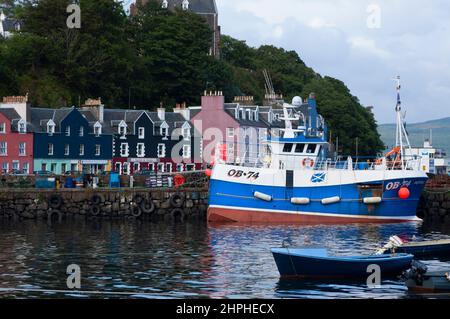 Barca da pesca di fronte alle colorate case sul lungomare di Tobermory sull'isola di Mull, Inner Hebrides, Scozia, Regno Unito Foto Stock