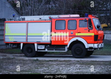 Auto rossa con motore antincendio parcheggiata con scala di emergenza senza vigili del fuoco al tramonto Foto Stock