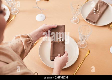 Vista dall'alto primo piano della giovane donna che decora il tavolo da pranzo in delicate tonalità di primavera con fiori dainty, spazio copia Foto Stock