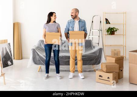 Giovane coppia che porta il cartone mentre si trova nel loro nuovo appartamento casa Foto Stock