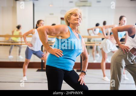 Ritratto di donna matura praticando danza balletto si muove durante la classe di gruppo in studio coreografico Foto Stock