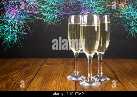 Primo piano di tre bicchieri di champagne su un tavolo di legno su sfondo nero con luccichini Foto Stock