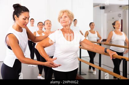 Varie donne anziane che esercitano il balletto si muove con il formatore Foto Stock