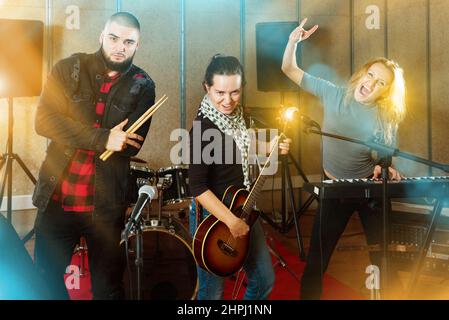 Tre bandmates che si posano insieme con strumenti musicali a rehe Foto Stock
