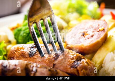 salsiccia alla griglia servita caldo, maiale affumicato tenuto da forchetta, punto focale, tradizionale pasto brasiliano Foto Stock