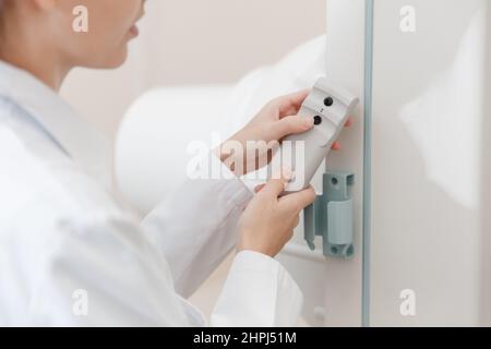 Sala di radiologia ospedaliera. Telecomando del dispositivo per fluorografia a raggi X. Radiologo medico in abito regolazione della macchina a raggi X per la radiografia. Medico Foto Stock