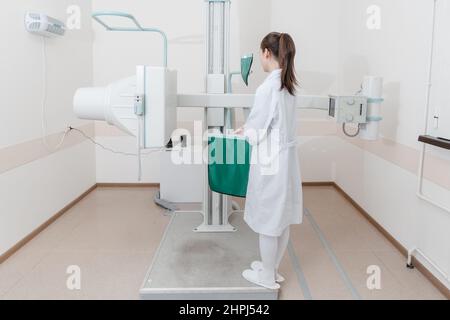 Sala di radiologia ospedaliera. Macchina a raggi X per fluorografia. Radiologo medico in abito regolazione della macchina a raggi X per la radiografia. Apparecchiature mediche Foto Stock