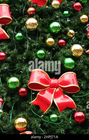 FIOCCHI DI CERAMICA ROSSI CON BORDI D'ORO E VERDI, SFERE ROSSE E D'ORO DECORANO UN ALBERO DI NATALE AD ADELAIDE, NEL SUD AUSTRALIA. Foto Stock