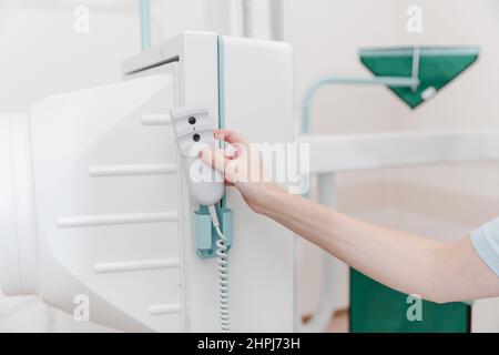 Sala di radiologia ospedaliera. Telecomando del dispositivo per fluorografia a raggi X. Radiologo medico in abito regolazione della macchina a raggi X per la radiografia. Medico Foto Stock