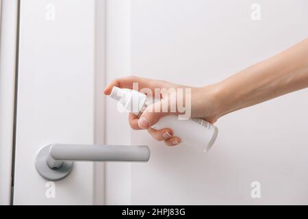 Pulizia delle maniglie bianche dello sportello con una salvietta antisettica bagnata e spray igienizzante. Disinfezione in ospedale e spazi pubblici contro il virus corona. Donna Foto Stock