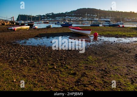 Barche illuminate dal sole pomeridiano a Teignmouth Devon, un luminoso pomeriggio invernale dove l'estuario incontra il mare, barche colorate in attesa della marea. Foto Stock