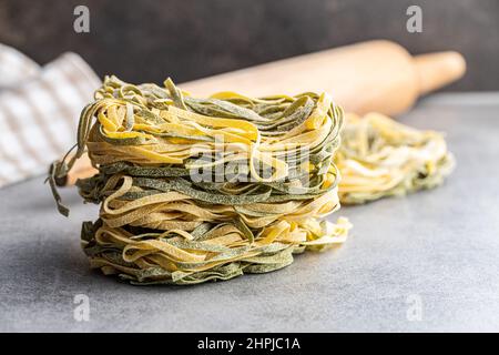 Pasta all'uovo. I tagliatelle si annidano con il sapore degli spinaci su un tavolo da cucina. Foto Stock