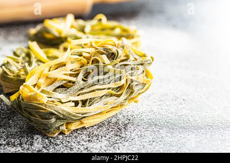 Pasta all'uovo. I tagliatelle si annidano con il sapore degli spinaci su un tavolo da cucina. Foto Stock