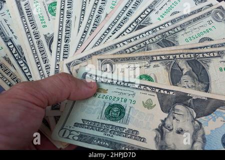 Mano maschile che tiene american Dollar-Bills. Direttamente sopra. Disposizione piatta. Finanza e business concept. Foto Stock