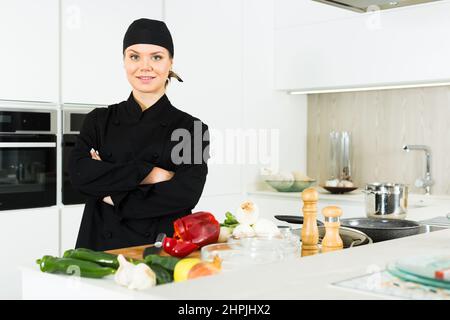 Professione di cuoco femminile al lavoro come donna in uniforme e cappello  bianco taglia il salmone su una tavola di legno in una cucina professionale  Foto stock - Alamy