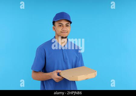 Giovane uomo di consegna in berretto su sfondo blu Foto Stock