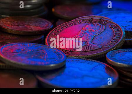 Colombiano un peso Coin 1974 Bolivar pile di monete Blu e Magenta Foto Stock