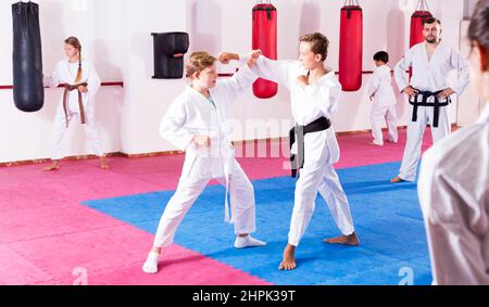 I bambini che lavorano in coppia padroneggiano le nuove mosse del karate Foto Stock