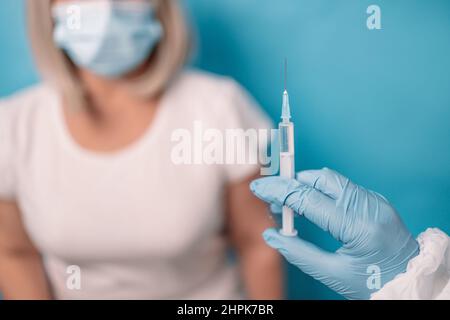 Primo piano del medico o dell'infermiere siringa con il vaccino Covid-19 con iniezione di richiamo scritta. Concetto di terza dose di richiamo del vaccino Foto Stock