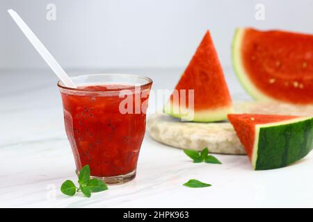 Bevanda a base di cocomero servita su vetro trasparente su sfondo bianco isolato. Fuoco selettivo con fette di frutta all'anguria. Spazio di copia per il testo. Foto Stock