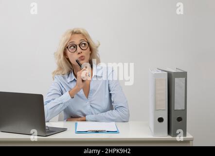Donna d'affari pensiva che pensa e guarda da parte lo spazio libero, seduto sul posto di lavoro, cercando di risolvere il problema aziendale Foto Stock