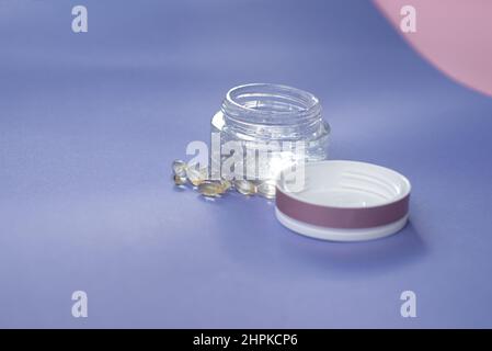 Gel con acido ialuronico in vaso di vetro e capsule su sfondo rosa Foto Stock