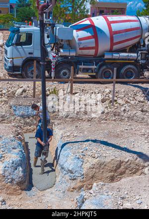 Travaso di calcestruzzo, che dirige la pompa e lavora in fondazioni. Foto Stock