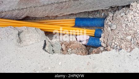 Il lavoratore inserisce cavi in fibra ottica interrati in una micro trincea Foto Stock