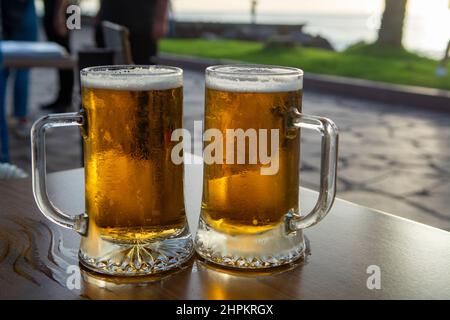 Due bicchieri da pinta con birra fredda serviti all'aperto al tramonto Foto Stock