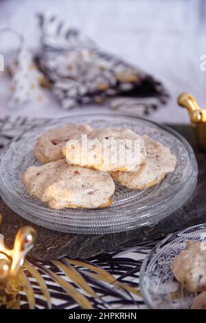 Biscotti fatti a mano con meringa e cioccolato su un piatto di vetro da dessert in un tavolo di Natale con decorazioni e candele Foto Stock