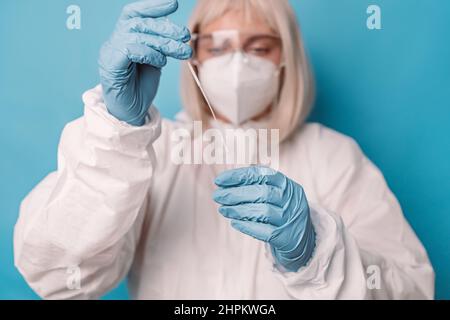 Test pcr Covid 19. Medico in tuta protettiva mascherina medica guanti tenendo tampone campione di saliva per la diagnostica covid 19 coronavirus virus in laboratorio. Foto Stock