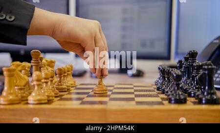 Un uomo d'affari con una pedina di scacchi nelle sue mani sta lavorando su una tastiera del calcolatore ad una scrivania dell'ufficio, primo piano Foto Stock