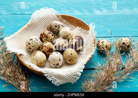 Mucchio di uova di quaglia in legno naturale ciotola di colore interno su legno asse sfondo blu. Concetto di cibo sano. Foto Stock