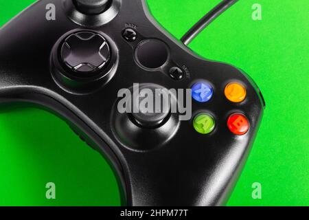 Primo piano della foto del classico controller wired moderno game pad che si trova su sfondo verde. Foto Stock