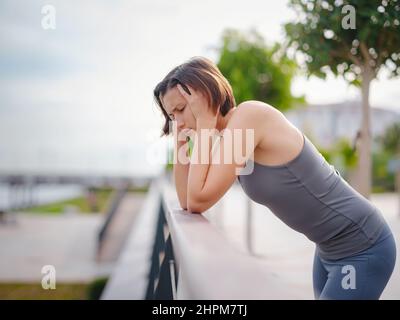 asian giovane forte, donna fiduciosa in abiti sportivi sensazione di male in procinto di buttare in su. Disidratazione. Dolore toracico. Cucitura laterale, crampi laterali dopo il funzionamento. Mal di stomaco dopo il jogging. Foto Stock