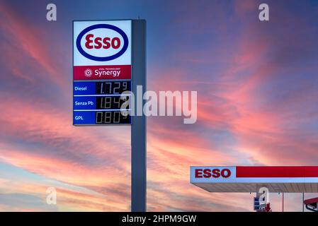 Fossano, Italia - 22 febbraio 2022: Logo esso con carburante visualizzazione del prezzo euro sul cielo al tramonto colorato, esso è un marchio dell'industria petrolifera globale gi Foto Stock