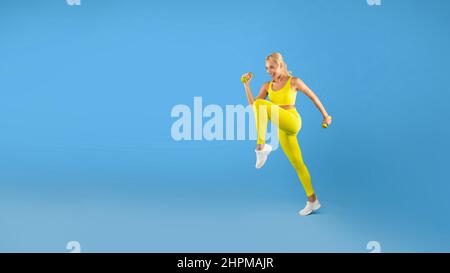 Giovane donna che si esercita con Dumbbells isolato su sfondo blu Foto Stock